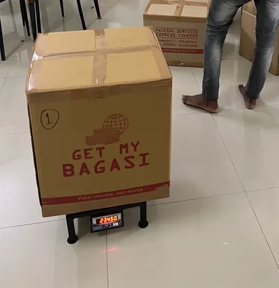 A packed carton on a digital scale showing 23.45 kg